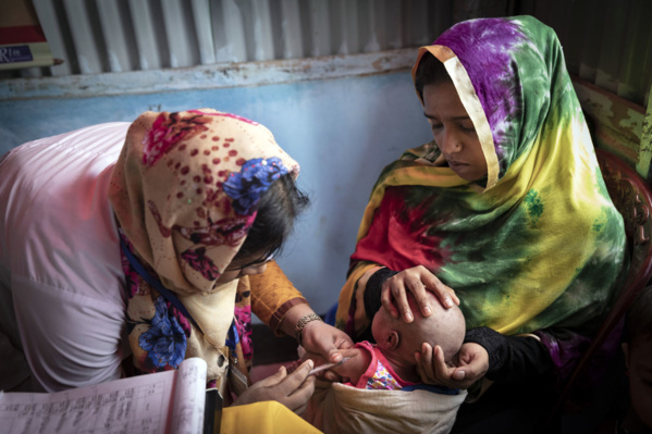 ©UNICEF/Brown Une volontaire d’un centre de santé dans l'un des vastes camps de réfugiés de Cox's Bazaar, au Bangladesh, inocule le bébé d'une mère de 18 ans.
